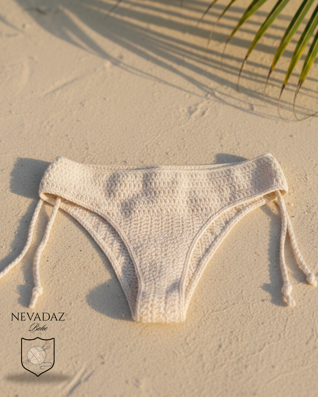 Beige bikini bottom on sand with palm leaf shadow
